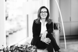 Sorthvit portrett av dame sittende ved et vindu i kontormiljø