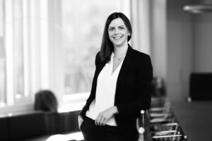 Sorthvit portrett av en dame med blazer stående med en hånd i lommen