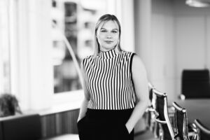 Portrett av en dame med en stripete topp i et kontorlandskap.