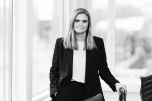 Sorthvit portrett av en dame som lener seg på en stol i et møterom