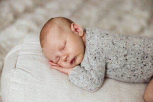 Baby sover magen med hånden under ansiktet