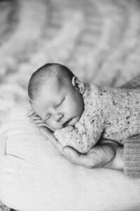 Nyfødt baby sovende i hånden til far i sorthvit